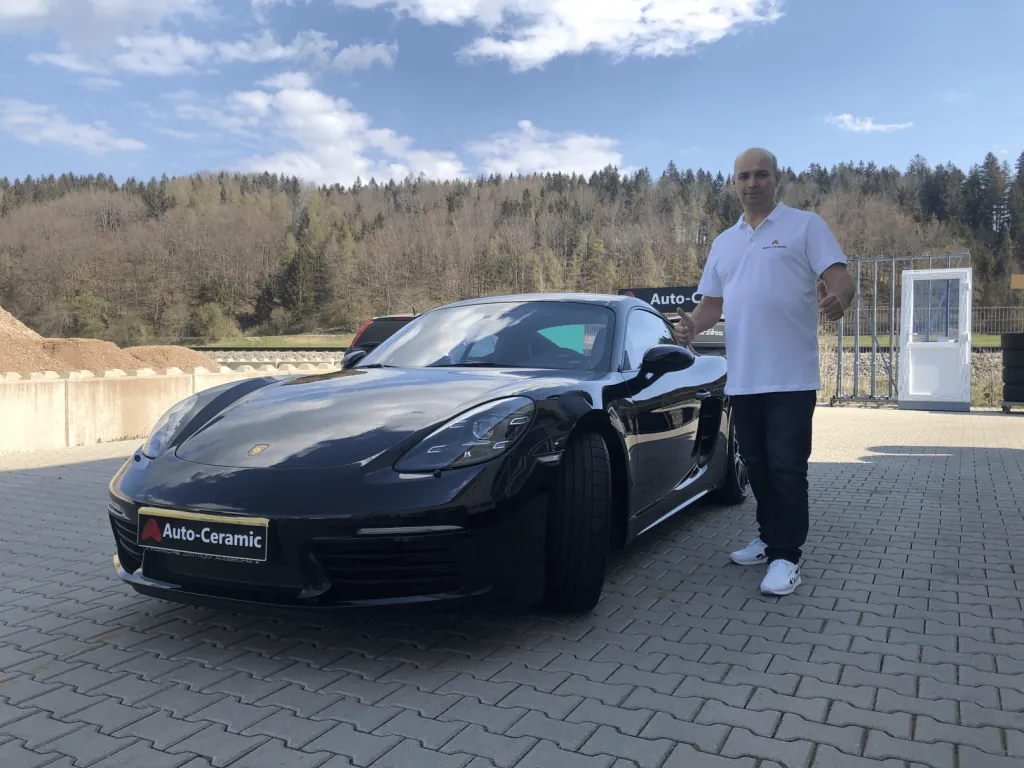 Sergej Gossen - Inhaber von Auto-Ceramic.de neben einem schwarzen Porsche Cayman nach Keramikbeschichtung